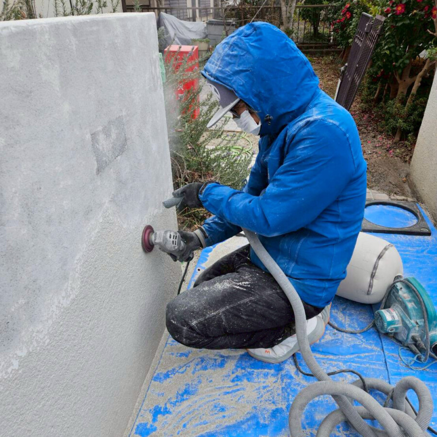 滋賀県草津市の外構リフォーム。門柱の塗り替えのためにサンダーを使って既存の塗装を丁寧に剥がしている様子。