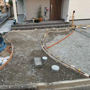 滋賀県大津市の新築外構現場にて、アプローチの美しい曲線を形作るコンクリート型枠の施工風景。