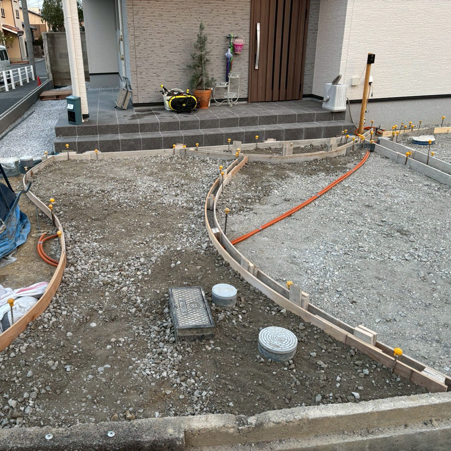 滋賀県大津市の新築外構現場にて、アプローチの美しい曲線を形作るコンクリート型枠の施工風景。