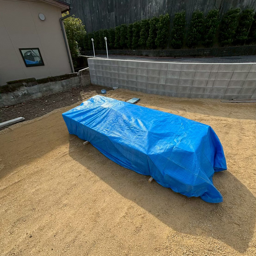 滋賀県大津市の新築外構現場にて、到着した外構資材をブルーシートで丁寧に養生して保管している様子。