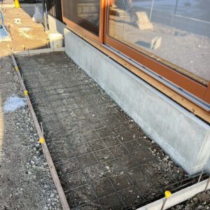 滋賀県豊郷町の新築外構現場にて、ウッドデッキの下をコンクリートで仕上げるために型枠を組み、ワイヤーメッシュを配置している様子。