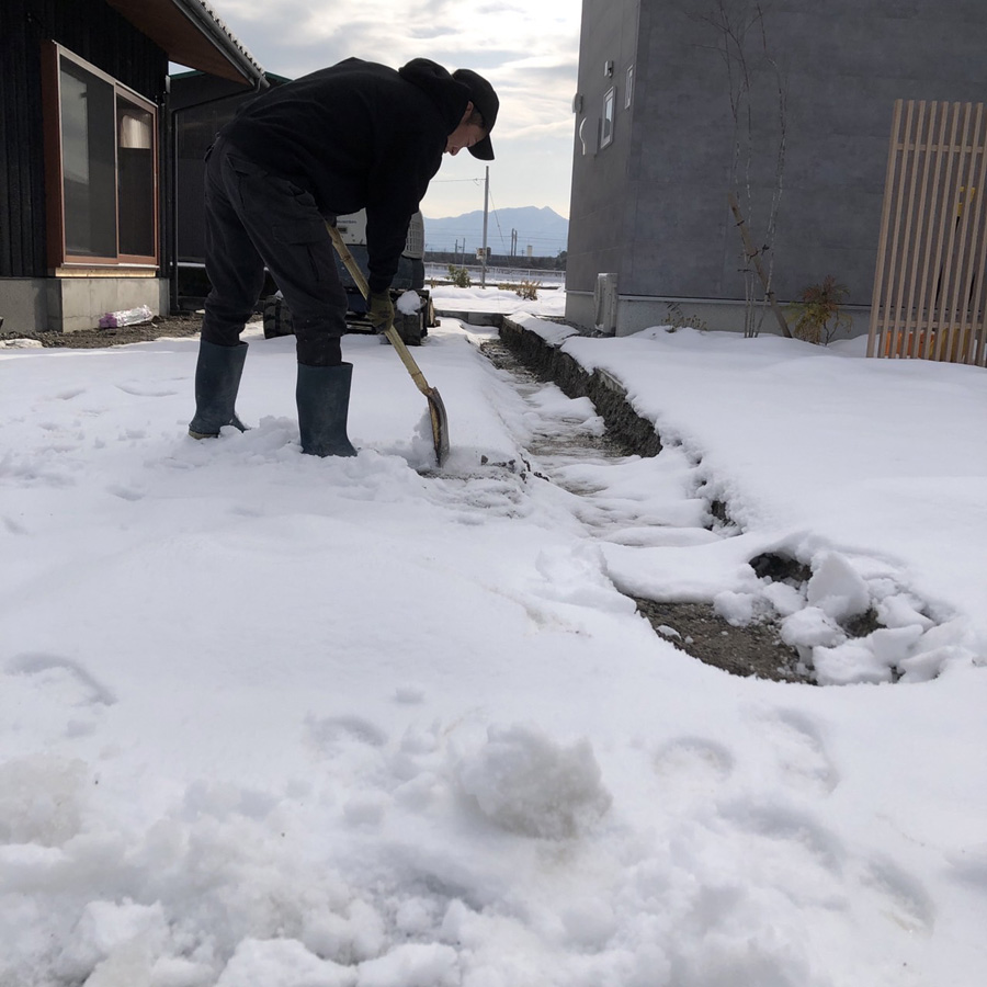 滋賀県豊郷町の新築外構現場。翌日の施工をスムーズに進めるために、職人が雪かきを行っている様子。