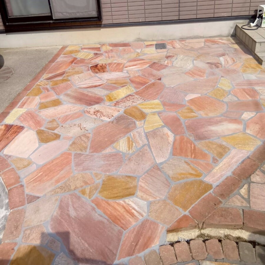 滋賀県草津市のリフォーム外構現場にて、アプローチ横の乱形石貼りが目地詰めと拭き取りを終えて完成した様子。
