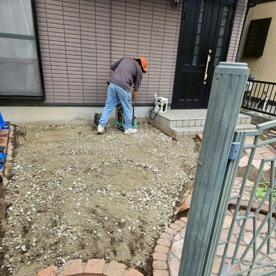 滋賀県草津市のリフォーム外構現場にて、アプローチ横の乱形石施工に向けた地盤調整を行っている様子。