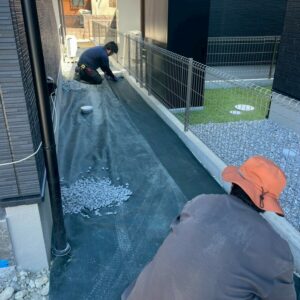 滋賀県草津市の新築外構現場にて建物の周りに防草シートを敷きその上に砂利を敷き詰めている様子。