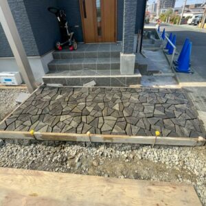 滋賀県草津市の新築外構現場にてユニソンの敷き材フィレットジオのランダムグレーをアプローチに施工している様子。