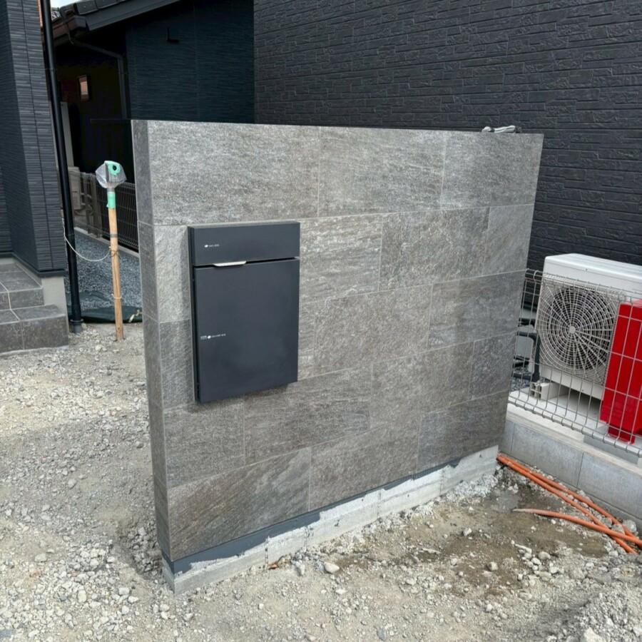 滋賀県草津市の新築外構現場にて東洋石創のタイル「ファインクォーツ」を貼った造作門柱にユニソンの宅配ボックス「ヴィコDB 100」を取り付けた様子。