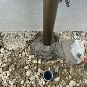 滋賀県近江八幡市の新築外構現場にてマエザワの立水栓メルスのシャンパンカラーを固定するためモルタルを塗っている様子。
