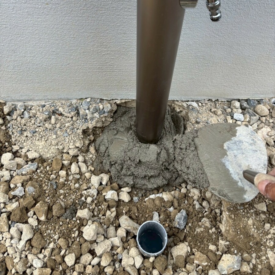 滋賀県近江八幡市の新築外構現場にてマエザワの立水栓メルスのシャンパンカラーを固定するためモルタルを塗っている様子。