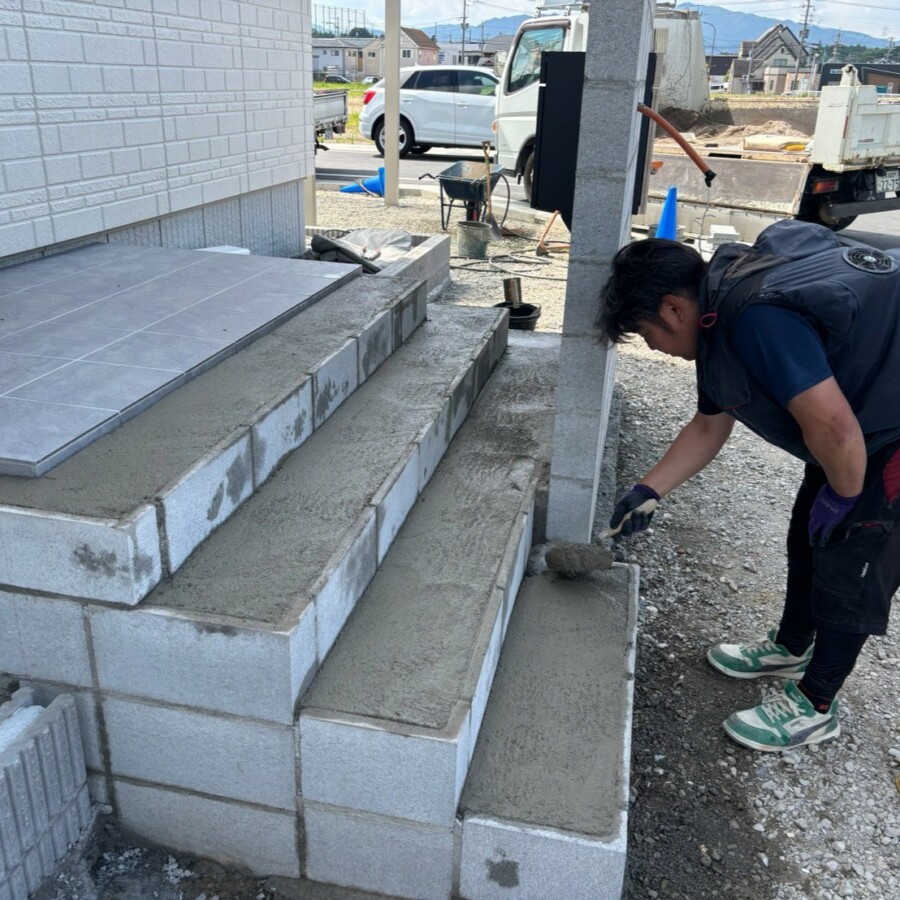 滋賀県湖南市の新築外構現場にて玄関ポーチ階段のタイル施工に向けてモルタル下地を塗る施工風景。