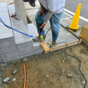 滋賀県湖南市の新築外構現場にて玄関階段のタイルに手すり支柱用の穴をコアドリルで開ける施工風景。