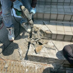 滋賀県草津市のリフォーム外構現場にて駐車場側の玄関階段の一部をハツリ解体する施工風景。
