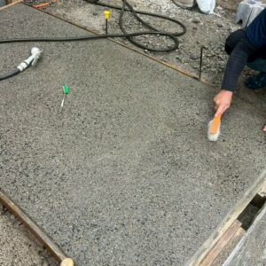 滋賀県草津市の新築外構現場にてアプローチの洗い出し仕上げで水とブラシを使い表面を洗い出す施工風景。