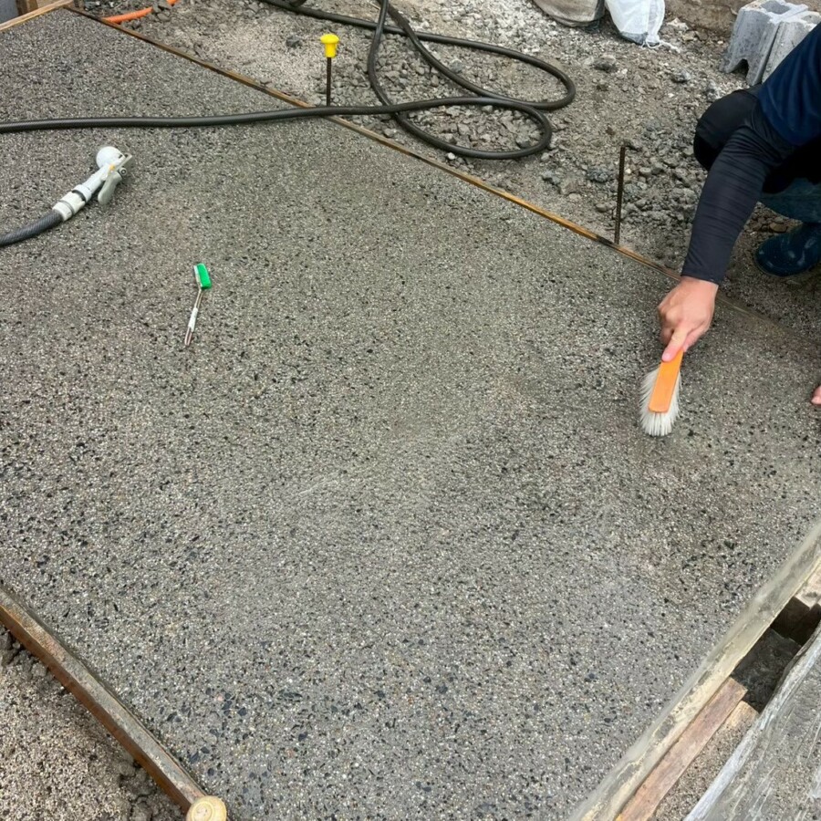 滋賀県草津市の新築外構現場にてアプローチの洗い出し仕上げで水とブラシを使い表面を洗い出す施工風景。