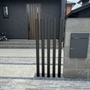 滋賀県草津市の新築外構現場にてタイル門柱の横に設置されたLIXILの枕木材R（ブラック・70×70角）。