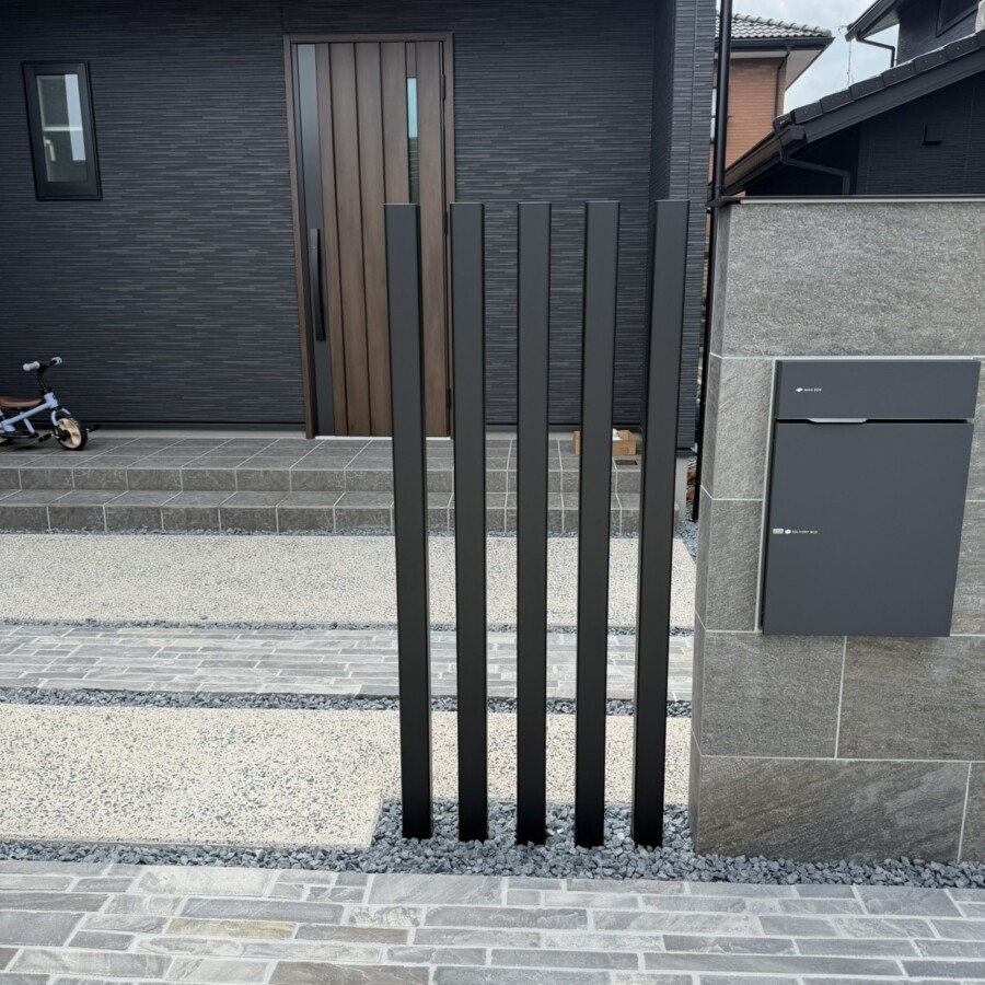 滋賀県草津市の新築外構現場にてタイル門柱の横に設置されたLIXILの枕木材R（ブラック・70×70角）。