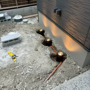 滋賀県草津市の新築外構現場にてタカショーのグランドライト「オルテックM」を配線・位置調整しながら設置する様子。