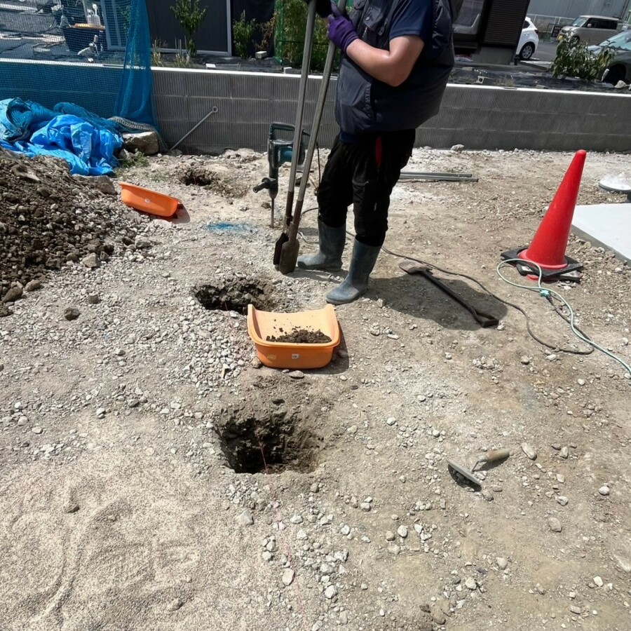 滋賀県栗東市の新築外構現場にて目隠しフェンスの支柱設置に向けて穴を掘削する施工風景。