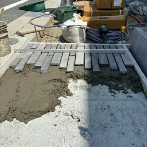 滋賀県湖南市の新築外構現場にてユニソンのフィットバトン（ランダムグレー）を敷き並べる施工風景。
