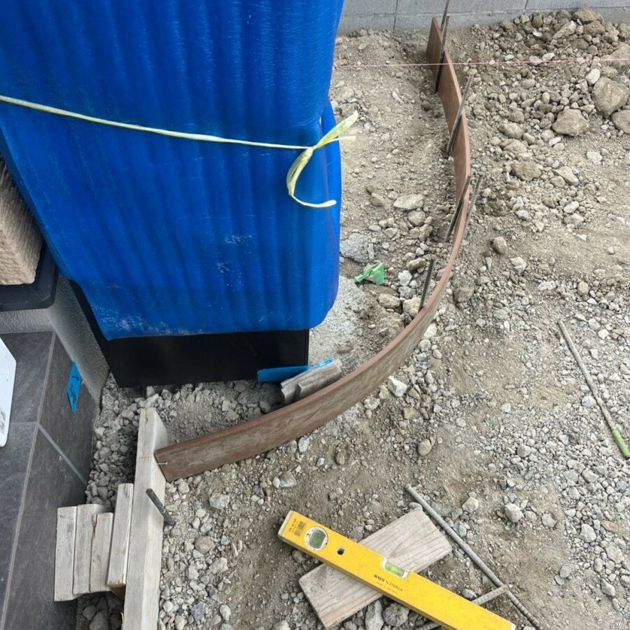 滋賀県草津市の新築外構現場にて機能門柱の足元に合わせたアーチ型のコンクリート型枠を設置する施工風景。