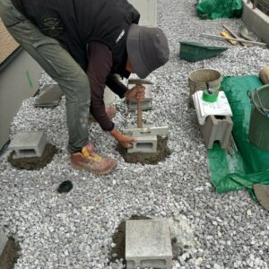 滋賀県草津市の新築外構現場にて物置設置用に基礎ブロックの水平調整作業を行う施工風景。