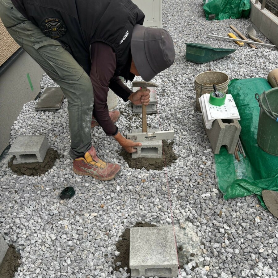 滋賀県草津市の新築外構現場にて物置設置用に基礎ブロックの水平調整作業を行う施工風景。