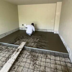 滋賀県栗東市の新築外構現場にてガレージ内の土間コンクリートをコテで敷き均す施工風景。