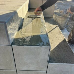 滋賀県湖南市の新築外構現場にて玄関アプローチ階段の踏み面と蹴上がりにタイルを張り付ける職人の施工風景。