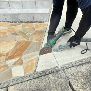 滋賀県竜王町の外構施工現場にて目隠しフェンス支柱設置のため土間コンクリートにカッターを入れる職人。