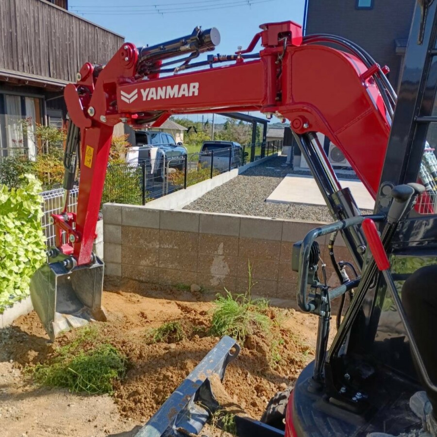 滋賀県竜王町の外構現場にて防草シートと砂利敷き施工の事前準備として重機で土を掘削・整地する風景。